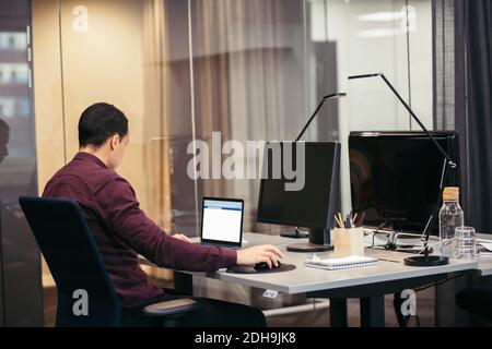Businessman working on laptop at desk in office Stock Photo