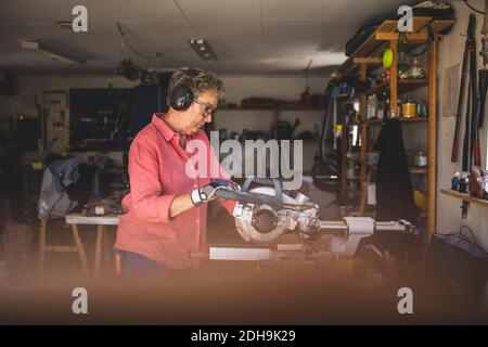 Senior woman using circular saw in workshop Stock Photo