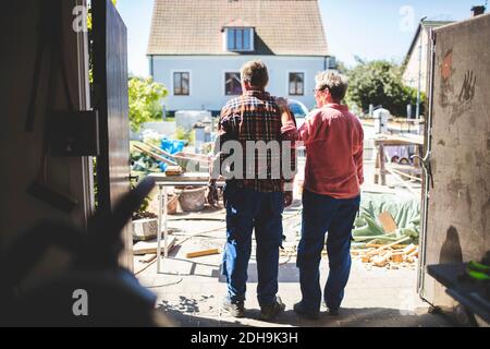 Rear view of senior couple looking at yard while standing in workshop Stock Photo