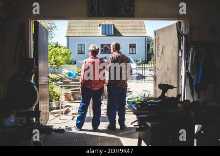 Senior couple looking at yard while standing in workshop Stock Photo