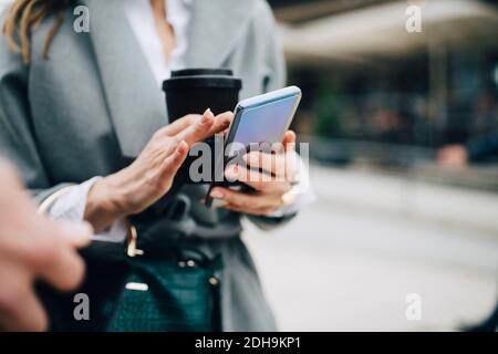 Midsection of businesswoman using phone in city Stock Photo