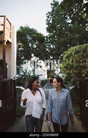 Female designers discussing while walking on footpath Stock Photo