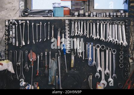 Various work tools hanging on wall at auto repair shop Stock Photo