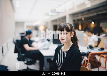 Portrait of confident computer programmer at office with colleagues working in background Stock Photo