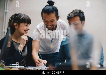 Happy computer programmer writing while discussing with colleagues in office Stock Photo