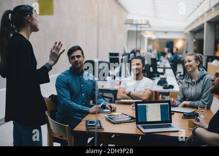 Female computer programmer giving presentation to colleagues in office Stock Photo