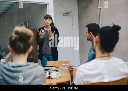 Female computer programmer giving presentation to colleagues in office Stock Photo