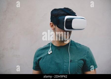 Computer programmer using VR glasses against beige wall in office Stock Photo