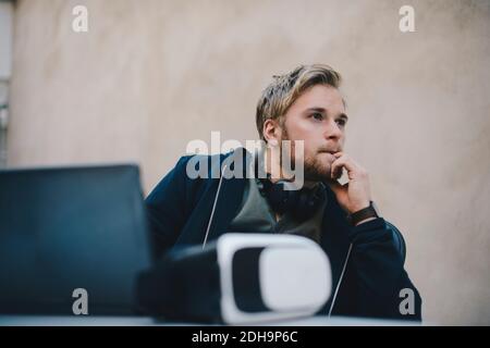Thoughtful computer programmer looking away while sitting at desk in office Stock Photo