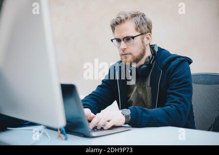 Male computer programmer using laptop at desk in office Stock Photo