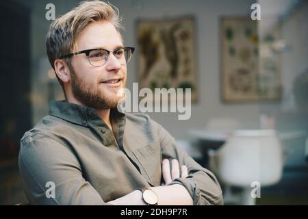 Thoughtful male computer programmer standing arms crossed in office Stock Photo