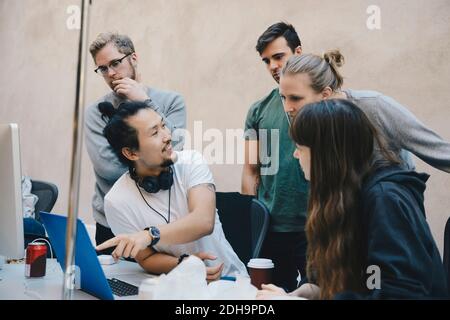 Male computer programmer showing laptop to colleagues in office Stock Photo