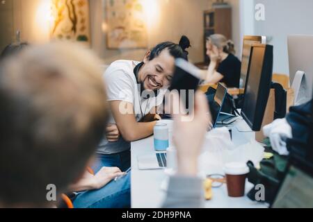 Happy computer programmer sitting with colleagues at desk in office Stock Photo