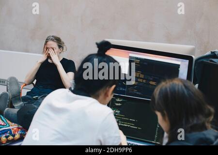 Male and female computer programmers using computer at office Stock Photo