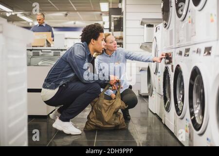 Mature owner explaining about washing machine to customer in electronics store Stock Photo