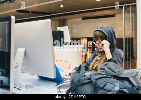Female computer programmer using laptop while looking over eyeglasses in office Stock Photo
