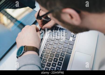 High angle view of computer programmer fixing digital tablet to keyboard at desk in office Stock Photo