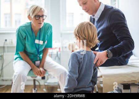 Rear view of boy standing by father while talking to doctor in clinic Stock Photo
