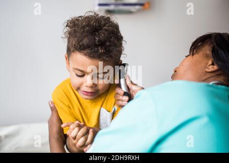 Female pediatrician examining boy's ear in medical clinic Stock Photo