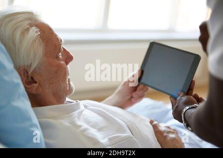 Cropped image of male nurse assisting senior man in using digital tablet at hospital Stock Photo