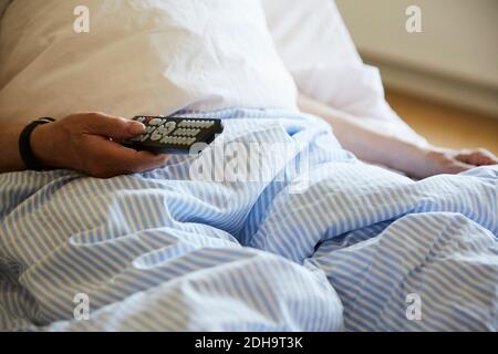 Midsection of senior man using remote control on hospital bed Stock Photo