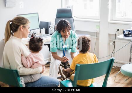 Smiling female doctor talking to boy while family in clinic Stock Photo