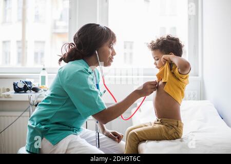 Female pediatrician examining boy's heartbeat in medical clinic Stock Photo
