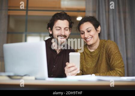 Smiling business colleagues using mobile phone at creative office Stock Photo