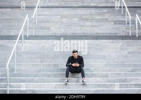 Young man using smart phone while sitting on staircase Stock Photo