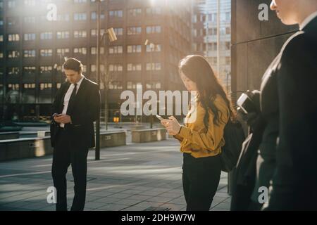 Three people standing in square using smartphones Stock Photo