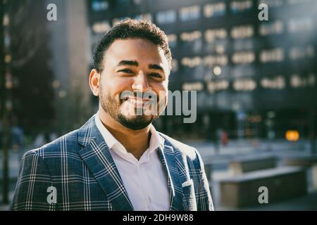 Portrait of smiling businessman standing outside office building Stock Photo