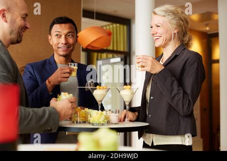 Smiling business people talking while drinking at office workshop Stock Photo