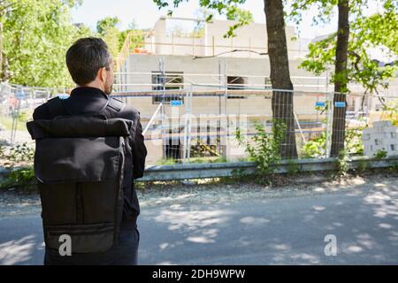 Rear view of architect standing by construction site on sunny day Stock Photo