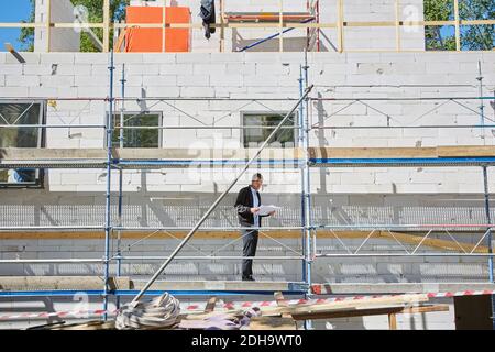 Full length of male architect with blueprint standing at construction site during sunny day Stock Photo