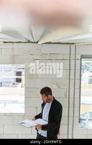 Mature architect reading document at incomplete building Stock Photo