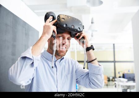 Smiling businessman wearing virtual reality stimulator at creative office Stock Photo