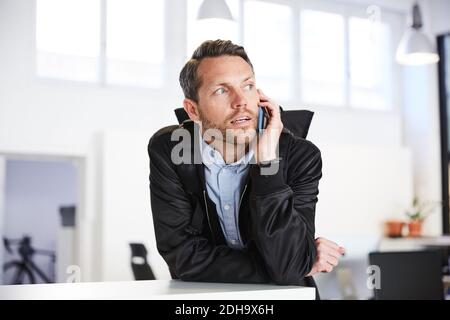Serious businessman talking on mobile phone at creative office Stock Photo