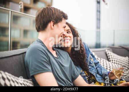 Smiling man with female partner on terrace during social gathering Stock Photo