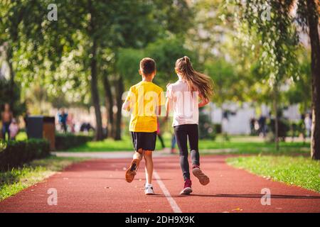 Sports and fitness in adolescence. Caucasian twins boy and girl run on ...