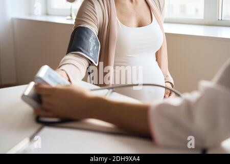 Doctor measuring blood pressure of her pregnant patient Stock Photo