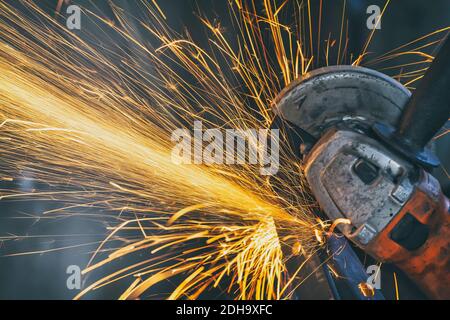 Using angle grinder, cutting metal, a lot of flashing sparks are flying. Stock Photo