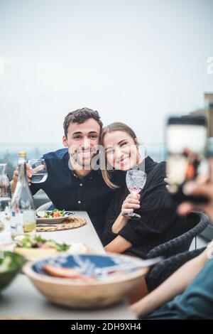 Happy friends with drinks posing for photograph during rooftop party Stock Photo