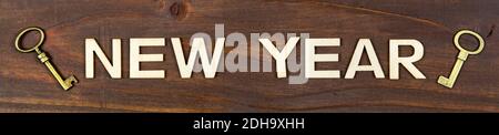 Happy new year letters with gold keys on wooden background, web banner Stock Photo