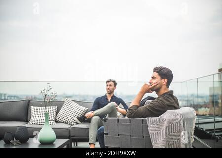 Young friends sitting on sofa at building terrace Stock Photo