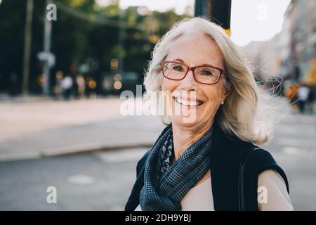 Portrait of happy wrinkled woman wearing scarf in city Stock Photo