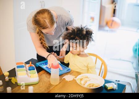 Mother assisting son in using digital tablet at home Stock Photo