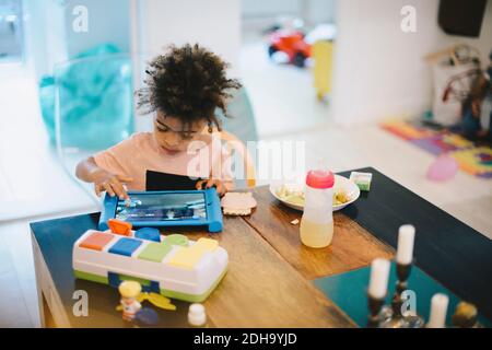 Boy using digital tablet while sitting at table Stock Photo