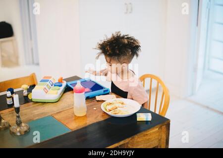 Boy using digital tablet while having food at table Stock Photo
