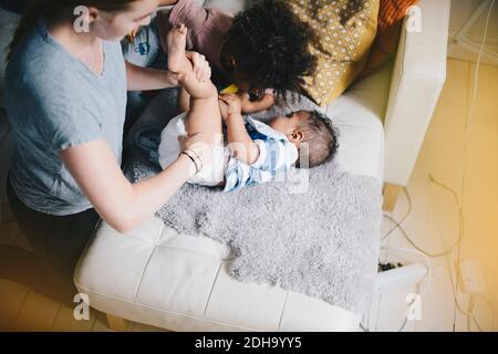 Boy playing while mother dressing son at sofa Stock Photo