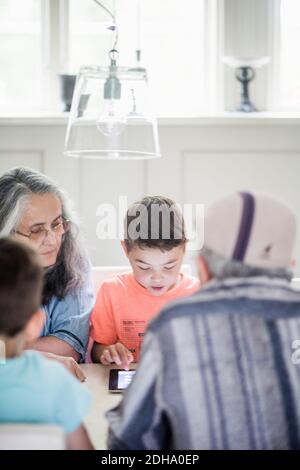 Grandparents looking at boy using digital tablet at home Stock Photo